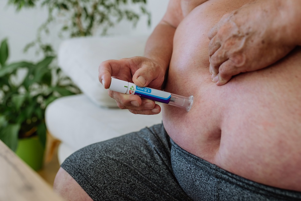 Overweight man with diabetes injecting insulin in his abdomen. Close up of man with type 1 diabetes taking insuling with insuling pen.