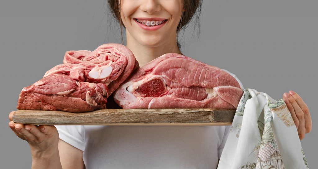 Unrecognizable woman holds wooden board with different cuts of fresh raw meat
